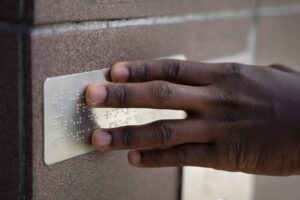 homme touche du braille sur une plaque murale